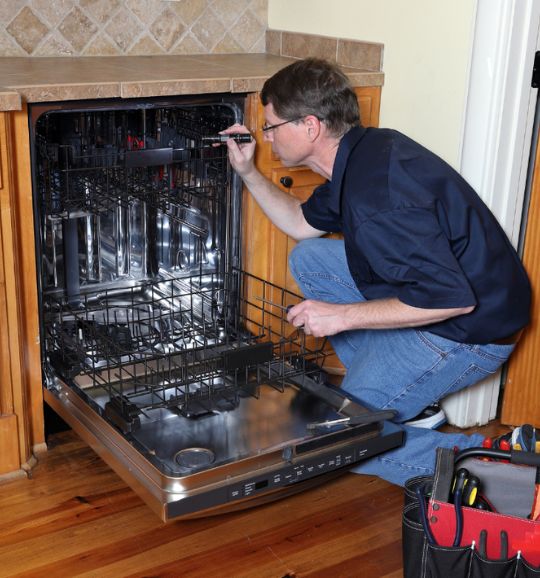 A man is engaged in repairing a dishwasher in a kitchen, highlighting appliance repair services available in San Antonio, TX.