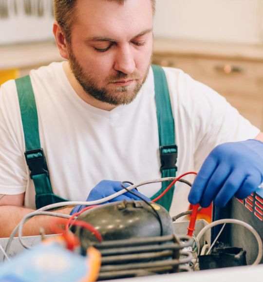 A man in an apron repairs a small appliance machine in San Antonio, TX, showcasing his expertise in appliance services.