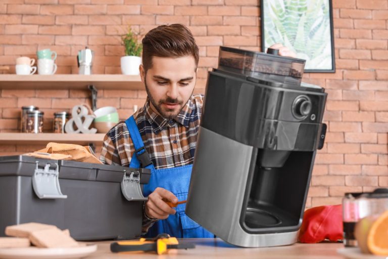 A man operates a coffee maker, preparing a fresh cup of coffee in a cozy kitchen setting.